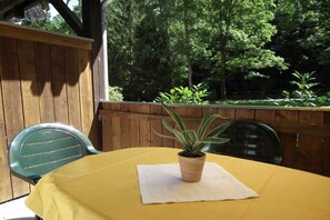 A yellow table with a potted plant on a white cloth, surrounded by wooden walls and green chairs. - Holiday apartment in Ilsenburg with terrace (Ilsenburg)
