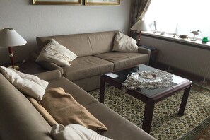 A living room with a sofa, two lamps, a coffee table, and a patterned rug. - Holiday apartment with 1 bedroom (Cuxhaven)