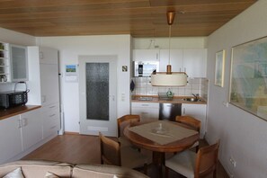 A compact kitchen with a dining area, wooden ceiling, and a map on the wall. - Holiday apartment with 1 bedroom (Cuxhaven)