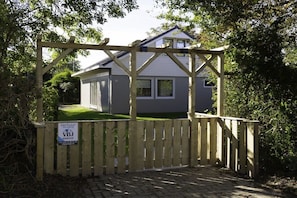 A gated entrance to a house with a wooden gate and a sign indicating it is for sale. - Holiday home with 2 bedrooms (Julianadorp aan Zee)