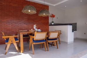 Un coin repas avec un mur en briques, une table en bois et des chaises dotées de coussins bleus.