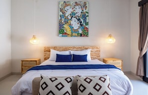 A bedroom with a bed, two bedside tables, a wall-mounted lamp, and a painting above the bed. - A tropical Bali villa with a private pool and peaceful vibes (Gianyar)