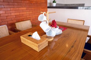 Un tavolo da pranzo in legno con un portaservizi di tessuto intrecciato, un tovagliolo rosso e un sottobicchiere bianco.