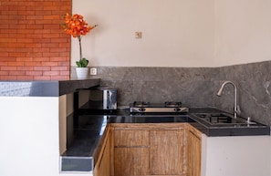 A compact kitchen with a built-in stove, a sink, and a wooden cabinet. - A tropical Bali villa with a private pool and peaceful vibes (Gianyar)