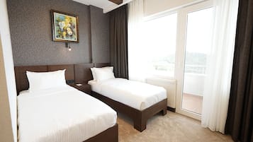 Una habitación de hotel con dos camas, un cuadro en la pared y vistas al exterior.