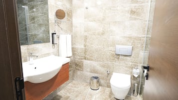 A bathroom with a sink, mirror, toilet, and shower.