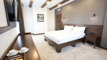 A hotel room with a bed, bedside table, and a wall-mounted TV.