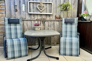 A patio with two plaid chairs and a table, a heart-shaped decoration, and a potted plant. - House Hölzene "Ilke" (Gersfeld)
