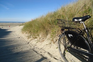 A bicycle parked on a sandy path beside a beach with grass on the side. - Holiday apartment with 1 bedroom (Borkum)