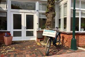 Een gebouwde ingang met een bord waarop 'Villa San Remo' staat en een fiets met een bezorgdoos geparkeerd ervoor.