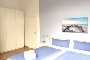 A bedroom with a bed, a nightstand, a lamp, and a painting of a coastal scene. - Holiday apartment with 1 bedroom (Borkum)