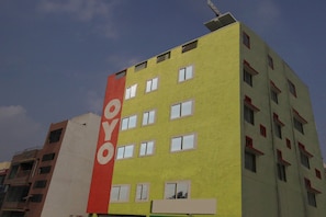 Un edificio de varios pisos con un cartel vertical llamativo en la fachada.