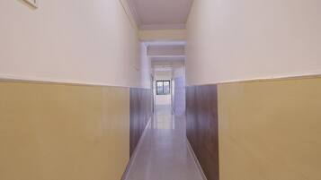 A corridor with a tiled floor, white walls, and a door at the end.