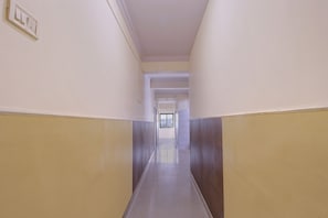 Un pasillo con piso de baldosas, paredes blancas y una puerta al final.