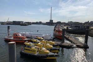 Ein Hafen mit mehreren vertäuten Booten, einem großen weißen Schiff und einem hohen Funkturm im Hintergrund.