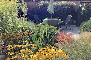 A patio with a table and chairs, surrounded by various plants and flowers. - Holiday apartment with 1 bedroom (Cuxhaven)