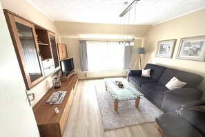 A living room with a sofa, a coffee table, a television, and a cabinet. - Holiday apartment with 1 bedroom (Cuxhaven)