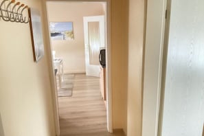 A hallway leading to a dining area with a table and chairs, a coffee machine, and a door. - Holiday apartment with 1 bedroom (Cuxhaven)