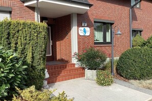 Ein Backsteinhaus mit einem Schild, das es als 'Friendlies' ausweist, einem kleinen Veranda und einem gepflegten Heckenstreifen.