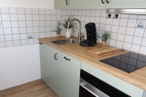 A kitchen with a sink, coffee maker, and a cutting board on the countertop. - 6 - Am Grooten Steen 1 (Cuxhaven-Duhnen)