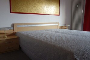 A hotel room with a bed, bedside tables, a lamp, and a large painting on the wall. - 18 in the Stranddüne house (Haffkrug)