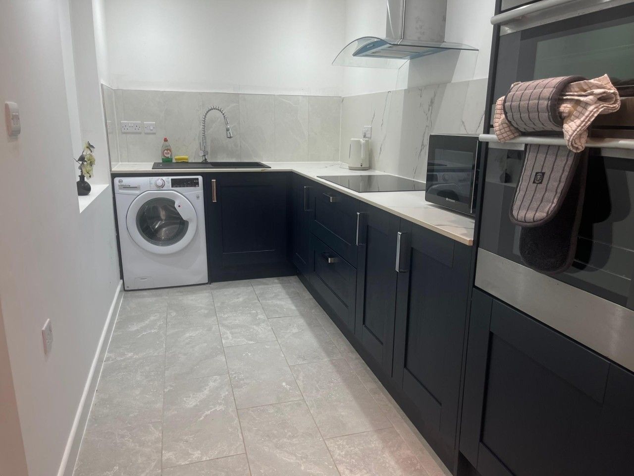 A compact kitchen with a washing machine, a microwave, and a stove.