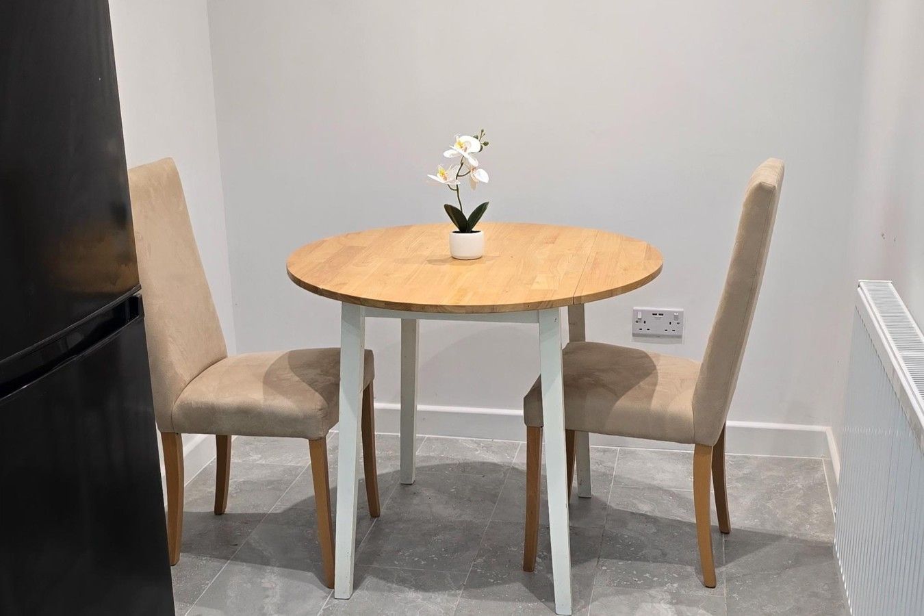 A dining area with a round wooden table and two beige chairs.