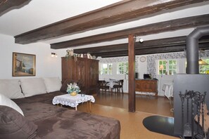 A cozy living room with a brown sofa, a dining table with chairs, and a kitchen area visible through an open doorway. - Holiday home with 1 bedroom (Kirchlinteln)