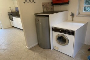 A compact laundry area with a washing machine and a compact dryer. - Holiday home with 1 bedroom (Kirchlinteln)