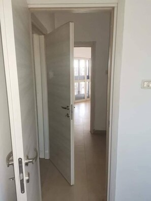 Una puerta abierta que da a una habitación con piso de baldosas y un ventanal.