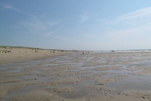 A beach with sand and water, some people, and dunes in the background. - Holiday home with 2 bedrooms (Julianadorp)