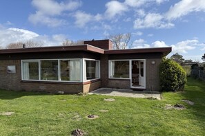 Een modern herenhuis met twee verdiepingen, een bakstenen gevel, grote ramen en een kleine voortuin.