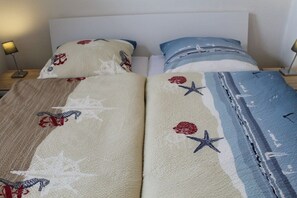 Ein Bett mit einer gestreiften Decke und Kissen mit floralen und Sternmotiven.