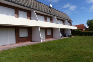 A two-story residential building with a flat roof, white exterior walls, and a brick foundation. There are three garage doors, one on each side of the building. - Holiday apartment Störtebeker's Cabin (Borkum)