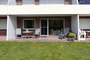 A residential building with a balcony, a sliding glass door, and outdoor furniture. - Holiday apartment Störtebeker's Cabin (Borkum)
