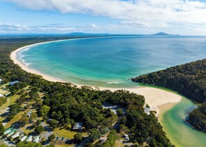 A coastal area with a beach, dense forest, and a clear sky. - Beachfront house, beautifully restored | Family & Pet friendly! (Hat Head)