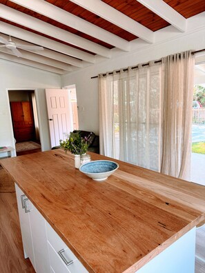 Cozinha com bancada de madeira, porta branca e vista para o exterior.
