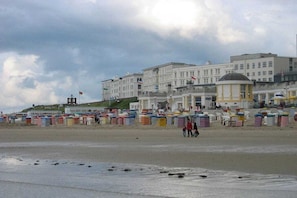A beach with a row of colorful beach huts and a building with multiple windows in the background. - Holiday home in Borkum with swimming pool (Borkum)