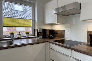 A modern kitchen with a stainless steel sink, a coffee maker, and a window with blinds. - Holiday apartment with 4 bedrooms (Borkum)
