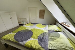 A bedroom with two beds, a crib, and a door. - Holiday apartment with 4 bedrooms (Borkum)