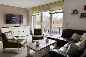 Een woonkamer met een bank, fauteuils, een salontafel en een televisie.