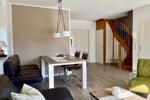 Een moderne woonkamer met een eethoek, een trap en een bank.
