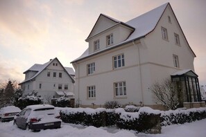 A multi-story residential building with a snow-covered roof and parked cars. - Holiday apartment with 2 bedrooms (Eschwege)