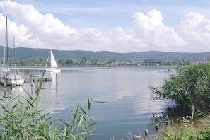 Ein ruhiger See mit Booten, einem kleinen weißen Turm und umliegender Vegetation.