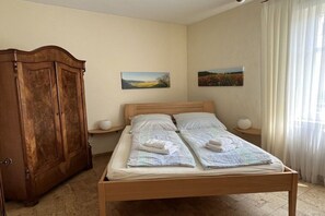 A bedroom with a wooden bed, two bedside tables, a wardrobe, and two landscape paintings on the wall. - Holiday apartment with 2 bedrooms (Eschwege)