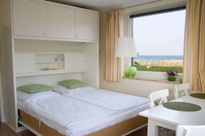 A room with a bed, a table, and a window with curtains. - Holiday apartment with 1 bedroom (Haffkrug)