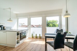 A modern kitchen with a dining area, large windows, and a view of the neighborhood. - in the Butenbörkumer house (Borkum)
