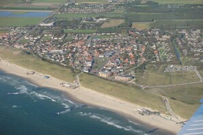 Luftaufnahme einer Küstenstadt mit Strand, Wohngebieten und einer Mischung aus Gebäuden.