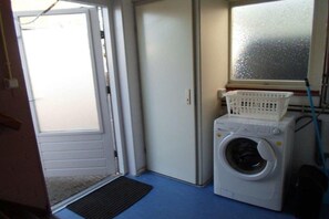 A laundry room with a washing machine, a dryer, a window, and a door. - Holiday apartment with 2 bedrooms (Callantsoog)