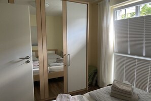 A bedroom with a wardrobe, a bed, and a window with blinds. - Holiday apartment with 1 bedroom (Timmendorfer Strand)
